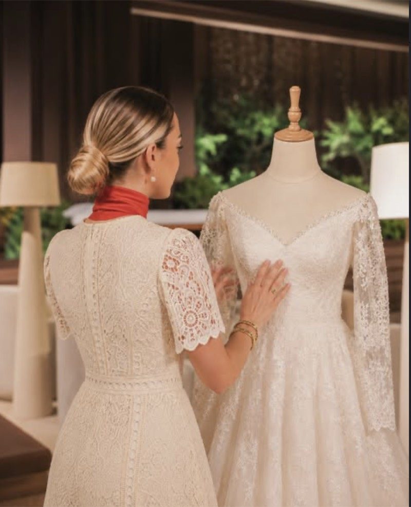 A Voil&agrave; Protocol hostess checking a lace wedding dress on a mannequin