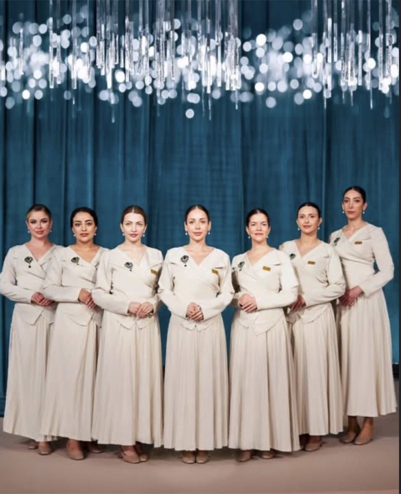 Seven Voil&agrave; Protocol hostesses against teal velvet under falling crystal