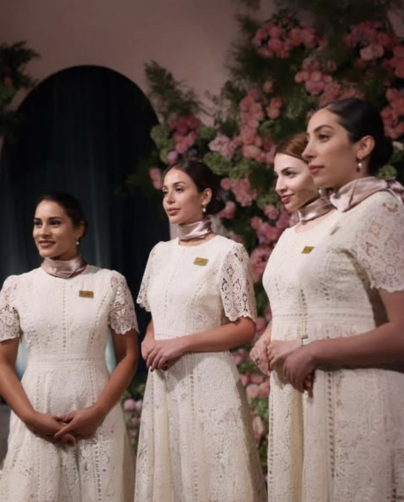 Four Voil&agrave; Protocol hostesses before an arch of pink roses