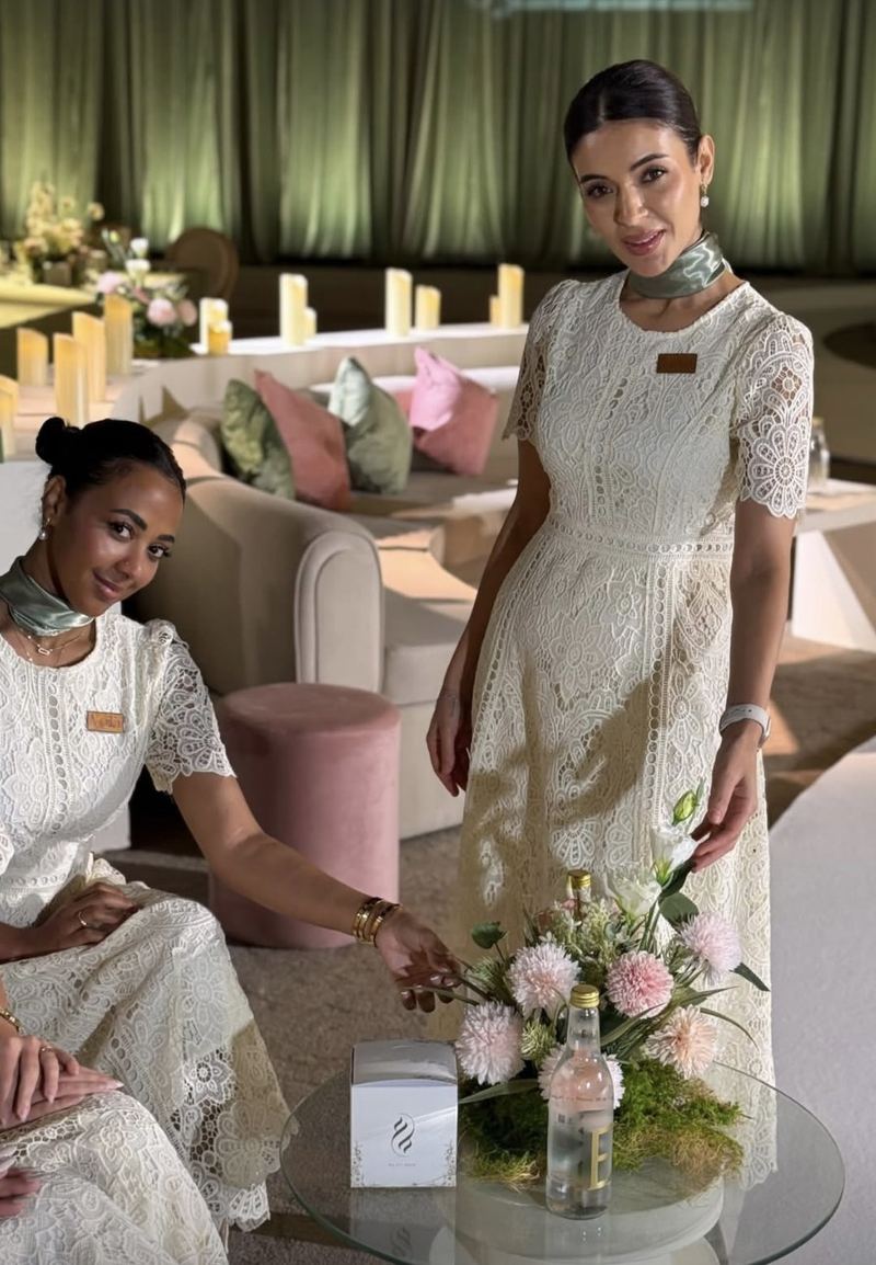 Two Voil&agrave; Protocol hostesses in the guest lounge beside the flower table