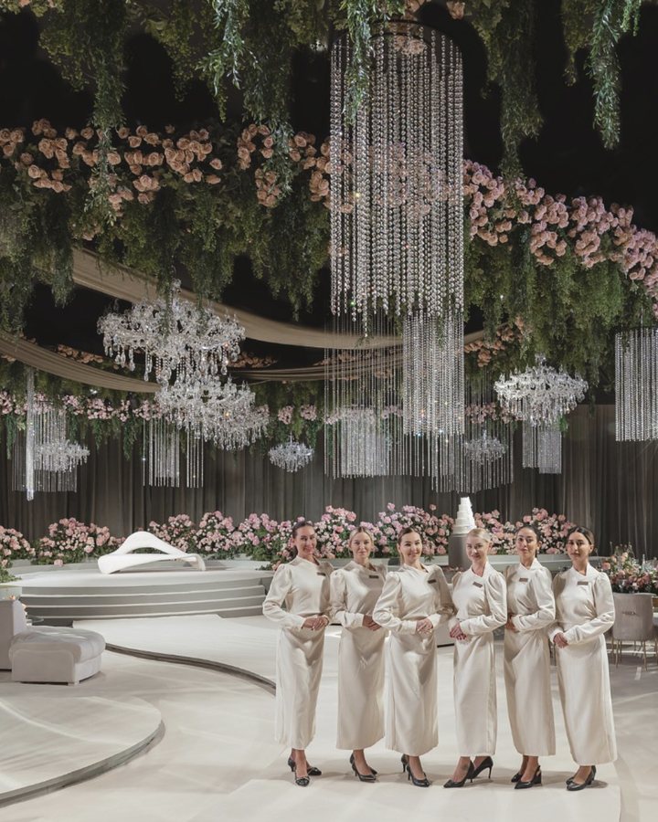 The Voil&agrave; Protocol team in uniform, in a ballroom hung with chandeliers and roses