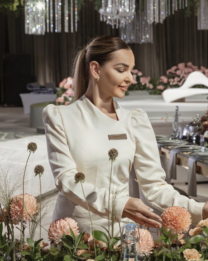 A Voil&agrave; Protocol team member setting a guest table, the gold Voil&agrave; badge on the uniform